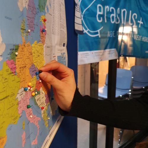 Eine Hand pinnt eine Nadel auf eine Europakarte