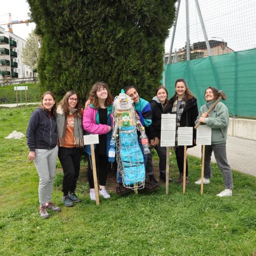 Die sieben ESK-Freiwilligen posieren am Weltacker Innsbruck mit dem von ihnen gebauten Mahnmal gegen Plastikverschmutzung