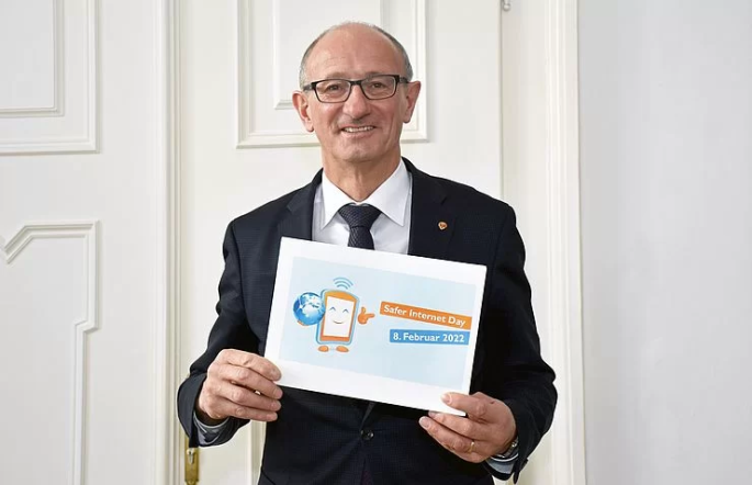Landesrat Anton Mattle hält das Logo zum Saferinternet Day 2022 in die Kamera.