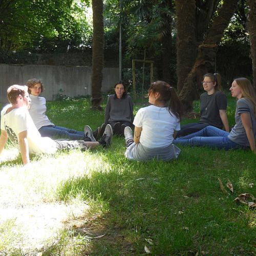 Jugendliche die im Gras sitzen.
