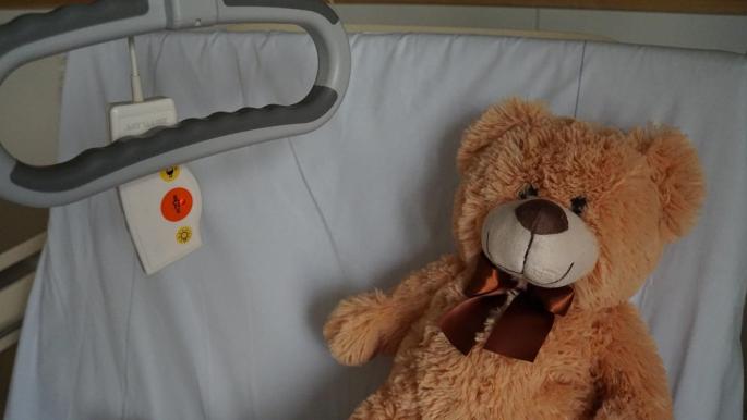 Ein brauner Teddy Bär liegt in einem Krankenbett