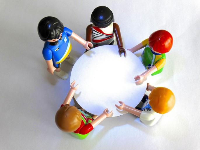 Bild: Fünf Playmobil Figuren stehen um einen Tisch