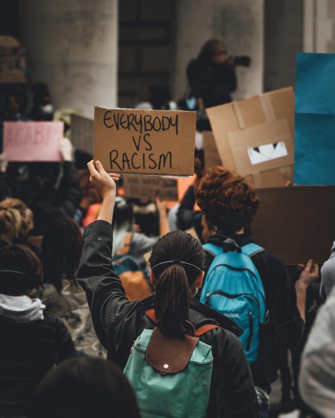 Eine Person in einer Demo hält ein Schild mit der Aufschrift "Everybody vs Racism".