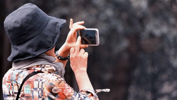 Eine Frau mit einer Mütze die ein Foto mit ihrem Smartphone macht.