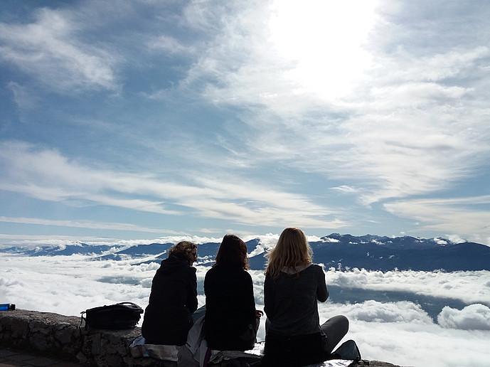 Drei Jugendliche sitzen auf der Seegrube in Innsbruck und blicken ins Tal. Es herrscht Sonnenschein.