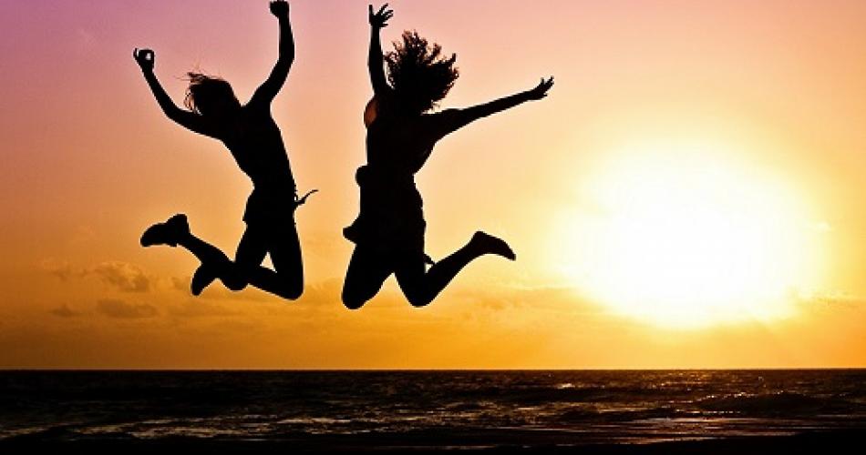 Zwei junge Leute die im Sonnenuntergang in die Luft springen.