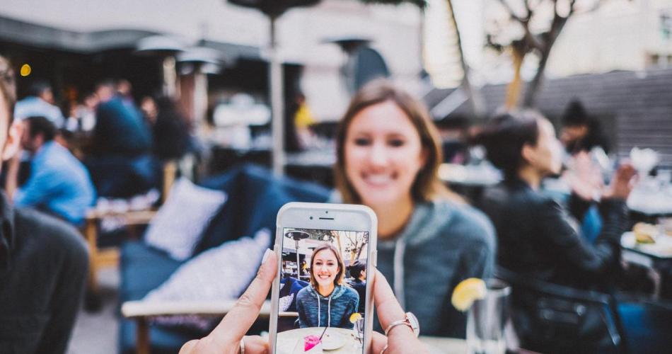 Junge Frau wird mit einem Smartphone fotografiert
