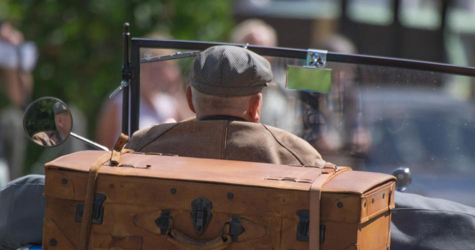 Älterer Mann in Auto mit Vintage-Koffer